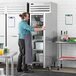 A man standing in front of a Beverage-Air stainless steel reach-in freezer with a solid door.