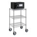 A black microwave on a Galaxy chrome shelf with casters.