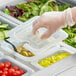 a hand in a glove holding a plastic container with food in it