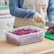 A person cutting red cabbage in a Vigor translucent plastic food pan.