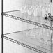 A Regency shelving unit with white vases and glasses on clear shelves.