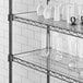 A white shelf with glass cups and vases on white Regency shelf liner.