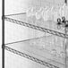 A clear Regency shelf liner on a shelf with white vases and glasses.