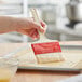 A hand holding a Choice natural bristle pastry and basting brush over a tray of dough.