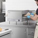 A man in a white apron using a Lincoln countertop conveyor oven to cook a sandwich.