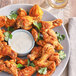 A plate of fried chicken wings with Regal Spicy Chipotle Wing Rub next to a bowl of white sauce.