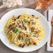 A plate of spaghetti with mushrooms and parmesan cheese with Regal Spaghetti Seasoning on a table.