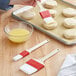 A person using a Choice polyester bristle pastry brush to paint a pastry on a surface.