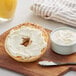 A bagel with Philadelphia Original cream cheese on a wooden board.