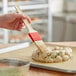 A person using a Thermohauser natural bristle pastry brush to brush braided dough.