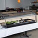 A black Carlisle tabletop buffet bar on a table with a glass case.