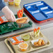 A person holding a Choice heavy-duty forest green melamine tray with 6 compartments filled with food, including a cup of carrots.