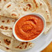 A plate of tortillas with a bowl of Ashoka Chatpata Achari red sauce.