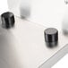 A Bunn stainless steel pour over coffee brewer with black knobs on a white counter.