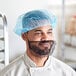 A man wearing a blue Choice disposable bouffant cap on his head.