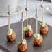 Front of the House Silver Bamboo Ball Picks with meatballs on a plate.