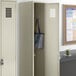 A beige metal locker with a blue and white striped bag inside.
