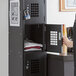 A woman opening a black metal Regency locker with white squares.