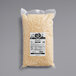 A package of Follow Your Heart Dairy-Free Vegan Shredded Parmesan Cheese on a gray surface.