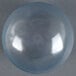 A clear glass globe on a grey surface with a white light inside.