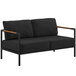 A black loveseat with wooden armrests and teak accents.