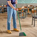 A man using a Libman Precision-Angle Broom to sweep a floor in a hospital cafeteria.