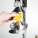 A person's hand squeezing a lemon into a white Choice cup on a white background.