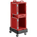 A red plastic container with a door on a dolly with wheels.