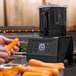 A person using a Sammic food processor to peel a carrot in a professional kitchen.