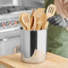 A stainless steel container holding wooden utensils.