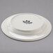 A white Tuxton saucer with an embossed rim.