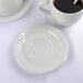 A white Tuxton saucer with a cup of coffee on a white table.