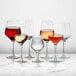 A group of Della Luce Astro all-purpose wine glasses filled with wine on a marble table.