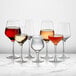 A group of Della Luce Astro wine glasses filled with wine on a marble table.