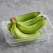 A plastic container with a bunch of green cooking bananas.
