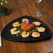 A black Elegance Triangle melamine plate with shrimp on a table.