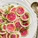 A white plate with a radish salad with sliced radishes, onions, and dill.