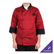 A person wearing a Chef Revival tomato red chef jacket with black pants.