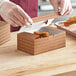 A gloved hand putting fried chicken into a Choice Cornerstone take-out box.