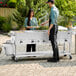 A man and woman using a Backyard Pro liquid propane steam table to serve food at an outdoor event.