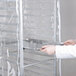 A person holding a Curtron clear plastic bun pan rack cover over a tray.