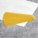 A close up of a yellow piece of Barilla Protein+ Angel Hair pasta on a white surface.