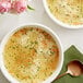 A bowl of Barilla pastina soup with a spoon and herbs.