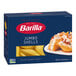 A blue box of Barilla Jumbo Shells Pasta with a picture of pasta shells on the front next to a plate of pasta.