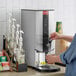 A person using a Grindmaster hot water dispenser to fill a coffee machine with water.