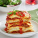 A plate of Barilla oven ready lasagna with a fork and a bowl of salad.