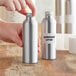 A person holding a silver aluminum bottle with a lid.