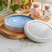 A silver round metal tin with a slip cover on a wood surface containing blue soap.
