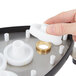A person holding a white plastic gear with a hole in the center.
