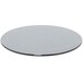 A round smoke tempered glass buffet board with a silver rim on a table.